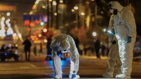 Reuters Forensics officers investigate the area of a bomb blast outside the Hellenic Train offices, in Athens