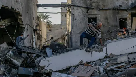 EPA Palestinians inspect the destroyed building of Al Ahli Baptist hospital following Israeli air strike in Gaza City 